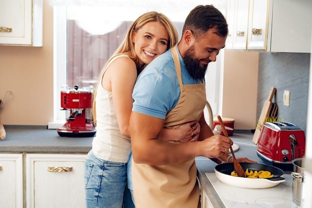 A husband is hugging his wife from behind while she is cooking in the kitchen. They are both smiling and enjoying each other's company.