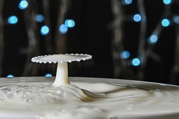 Close-up of a leaky faucet with visible water droplets forming at the base. The setting is a dimly lit bathroom, highlighting the waste of water.
