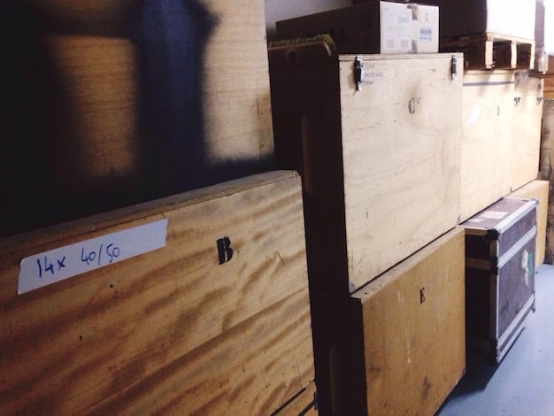 Close-up view of labeled storage boxes in an attic, showcasing a variety of handwritten labels indicating the contents, such as 