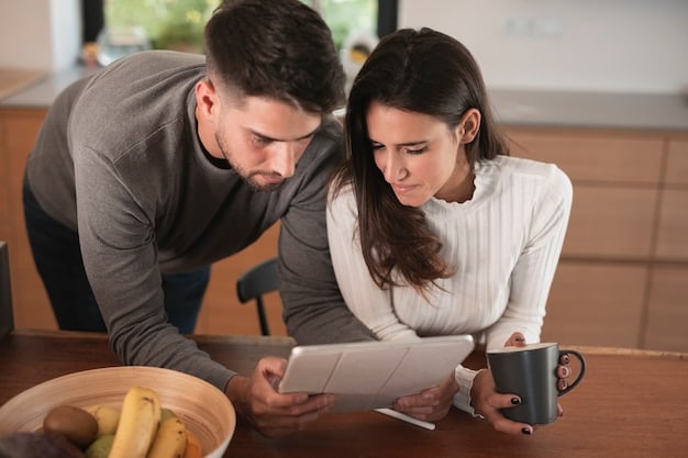 A couple sitting at a dining table, looking at financial documents and a tablet, symbolizing joint financial review and planning.