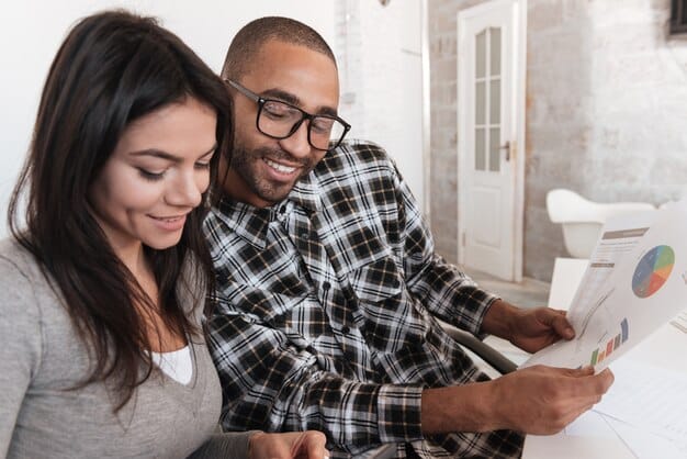 A diverse couple reviewing a financial spreadsheet on a tablet, with a stylized 2025 calendar in the background, signifying future planning.