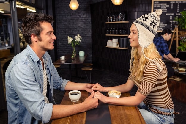 A couple sitting across from each other at a coffee shop, hands clasped, engaged in a serious but calm discussion. There's a notebook and pen on the table between them, suggesting structured communication.