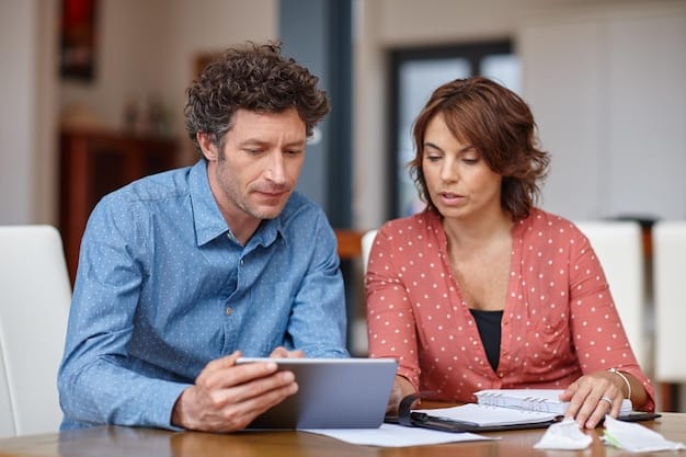 A couple sitting at a desk, looking at a tablet with a budgeting app, one pointing to the screen, both engaged in the financial planning process. Bright, modern office setting.