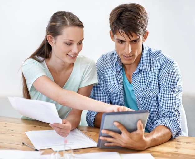 A couple reviewing documents and financial spreadsheets on a tablet, with a focused and collaborative expression, indicating financial planning.
