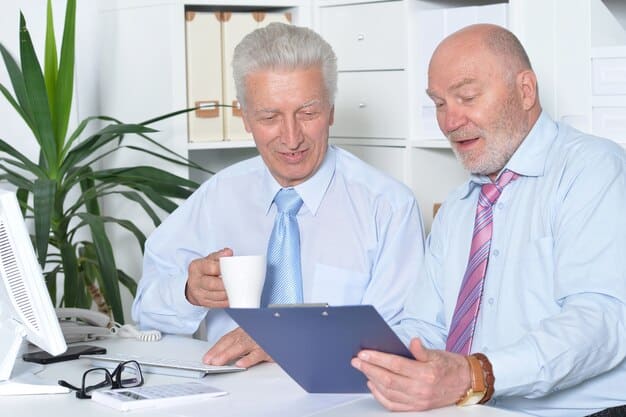 An older man and woman are discussing health plan documents with a friendly insurance agent in a comfortable office setting, highlighting personalized assistance.