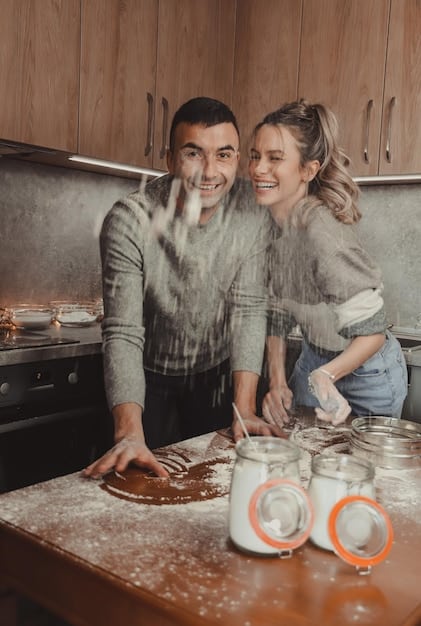 A happy couple laughing as they try to make homemade pasta together in a bright kitchen, with flour smudges on their faces, symbolizing a shared, joyful new experience.