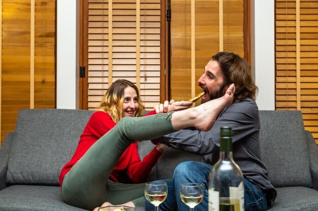 A couple laughing genuinely while sitting on a cozy sofa, perhaps sharing a lighthearted moment or a private joke. The background is a warm, inviting living room.