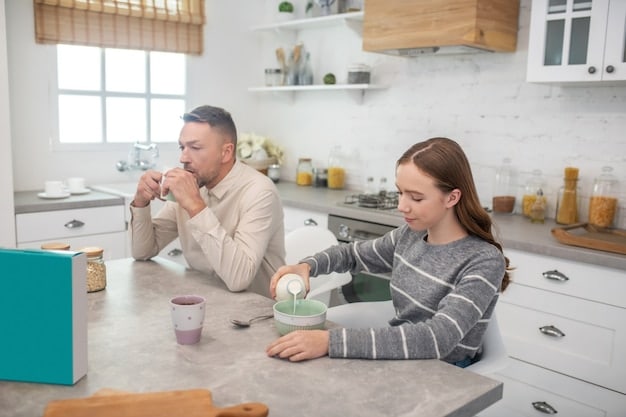 A couple sitting across from each other at a kitchen table, engaged in deep, empathetic conversation, with mugs of tea.